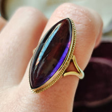 Load image into Gallery viewer, A yellow gold navette shaped cabochon cut amethyst solitaire ring, modelled on a hand

