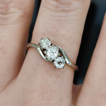 Load image into Gallery viewer, A three stone diamond trilogy ring in yellow gold and platinum, modelled on a hand
