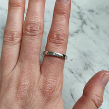 Load image into Gallery viewer, A round diamond set wedding band in white gold, modelled on a hand
