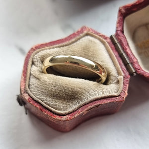 Gold ring in an open antique ring box on a white background