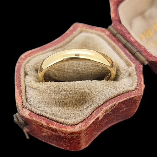 Gold ring in an open antique ring box with a black background