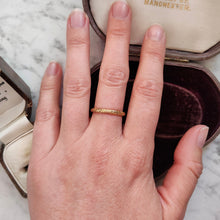 Load image into Gallery viewer, A yellow gold floral patterned wedding band ring, modelled on a hand
