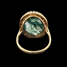 Load image into Gallery viewer, An oval moss agate ring in yellow gold, on a black background
