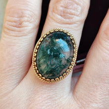 Load image into Gallery viewer, An oval moss agate ring in yellow gold, modelled on a hand
