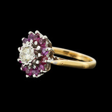 Load image into Gallery viewer, A circular ruby and diamond cluster ring in yellow and white gold, on a black background
