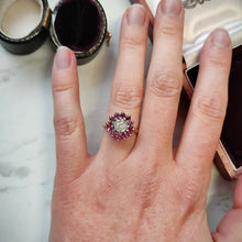 Load image into Gallery viewer, A circular ruby and diamond cluster ring in yellow and white gold, modelled on the ring finger of a hand
