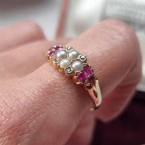 Gold ring with pearls, diamonds and rubies on a finger