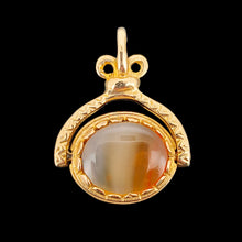 Load image into Gallery viewer, An oval spinner fob pendant in yellow gold with agate, on a black background
